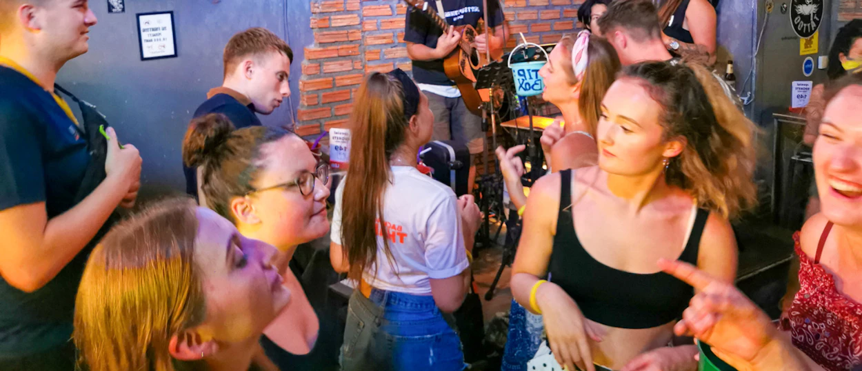 A lively group of young backpackers enjoying live music and drinks at a bar on Koh Phi Phi.