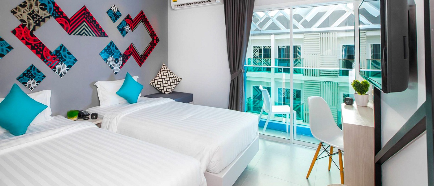 Modern hotel room with double bed and colorful decor at The Crib hotel in Phuket