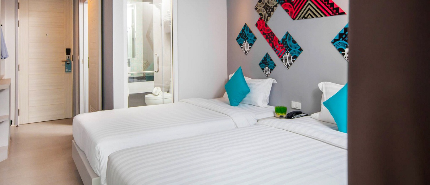 Modern hotel room with double bed and colorful pillows at The Crib hotel in Phuket
