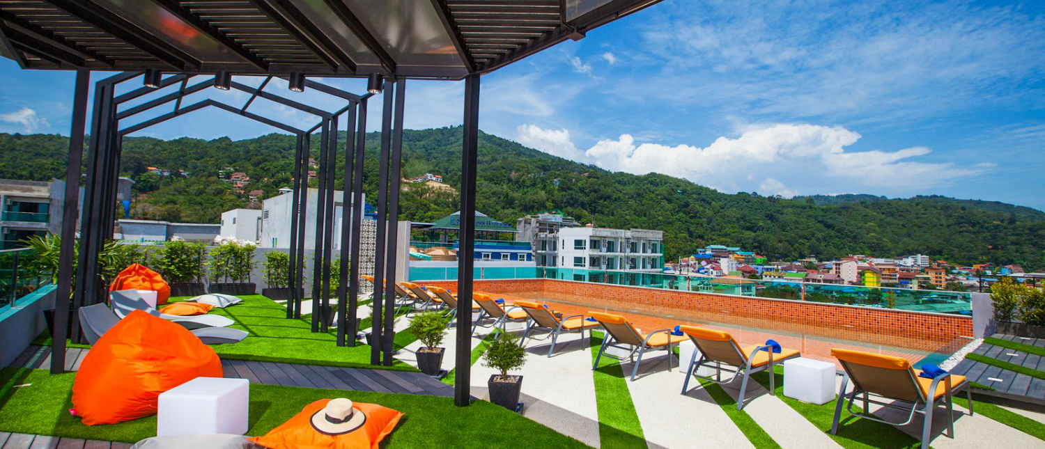 Rooftop terrace with orange lounge chairs and city views at The Crib hotel in Phuket