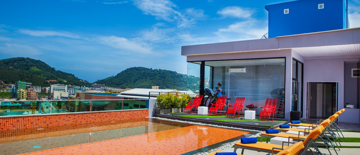 Exterior view of The Crib hotel in Phuket with mountain backdrop and modern design