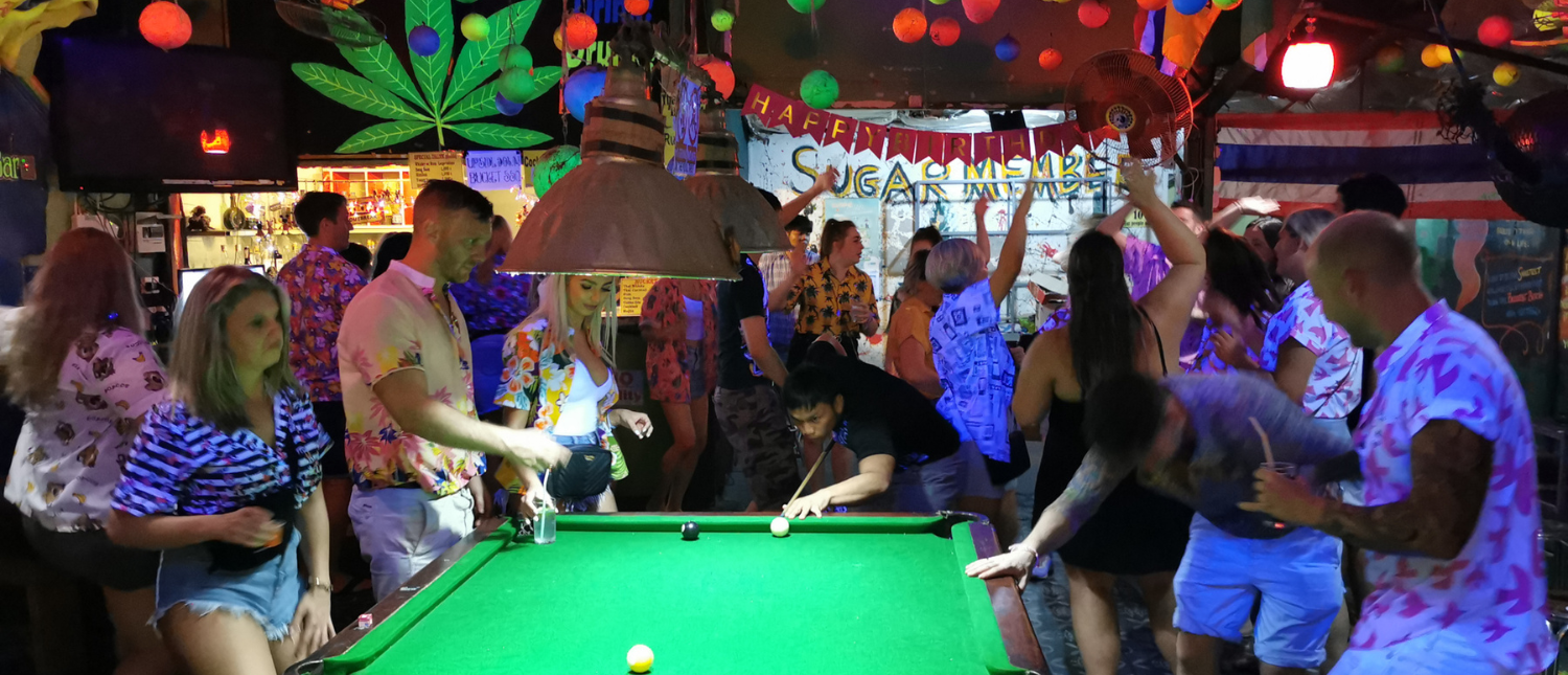 Backpacking group playing pool at a lively bar after a day at the elephant sanctuary