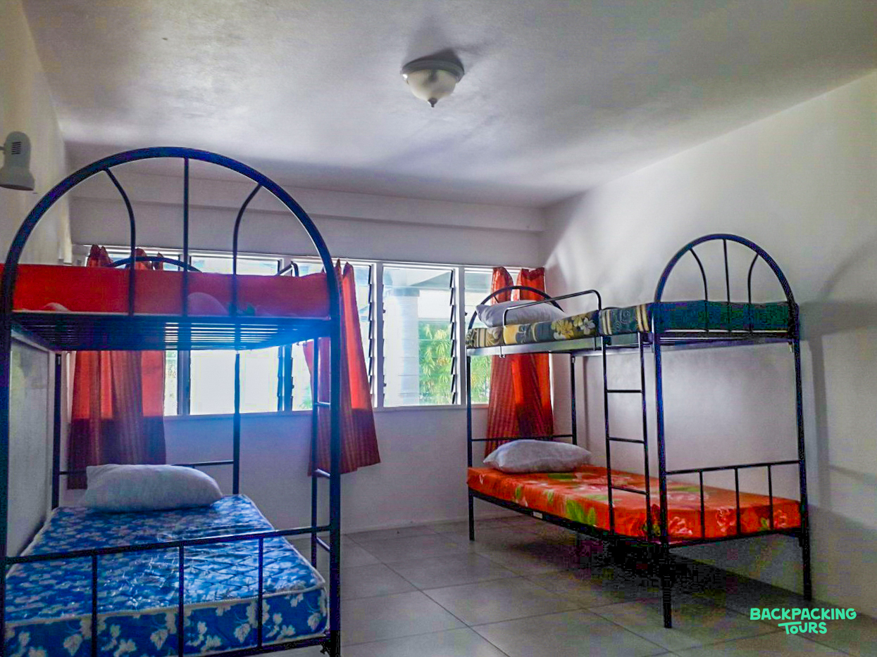 Two sturdy metal bunk beds with patterned mattresses in a bright, basic accommodation room.