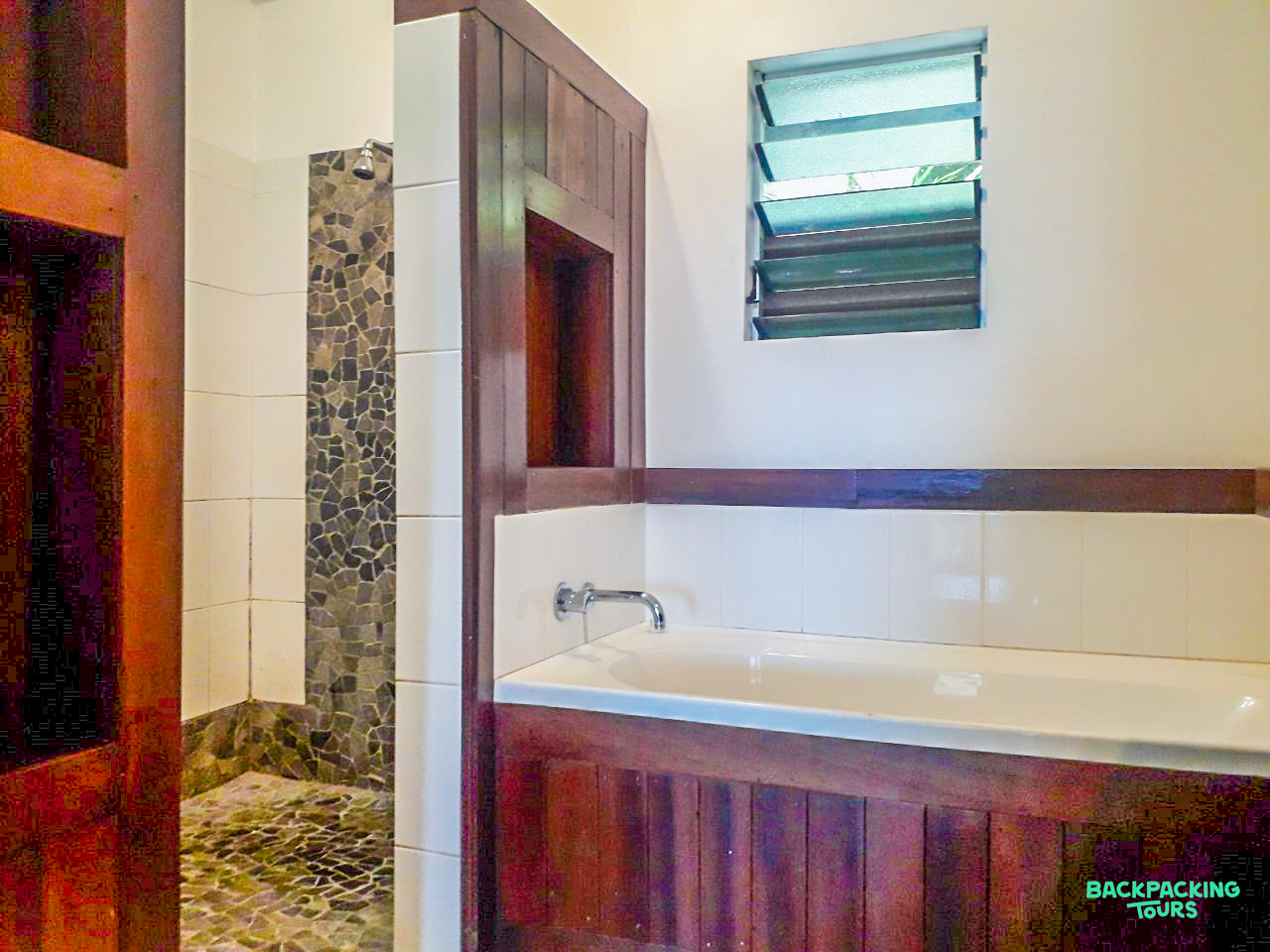 Relaxing bathroom with a deep soaking tub, elegant dark wood, and a natural stone shower area.
