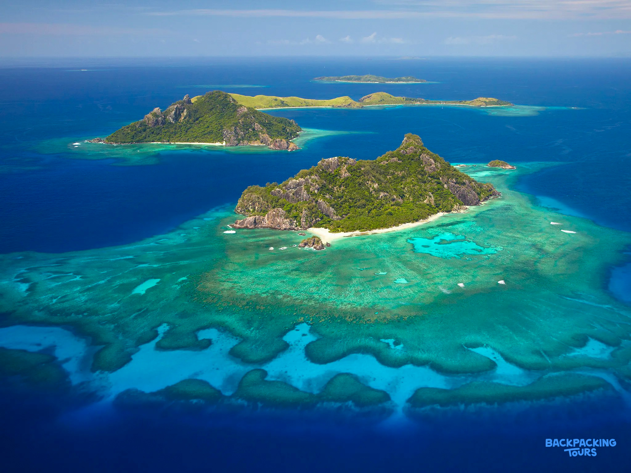 Lush tropical islands rise from vibrant turquoise waters and coral reefs in Fiji.