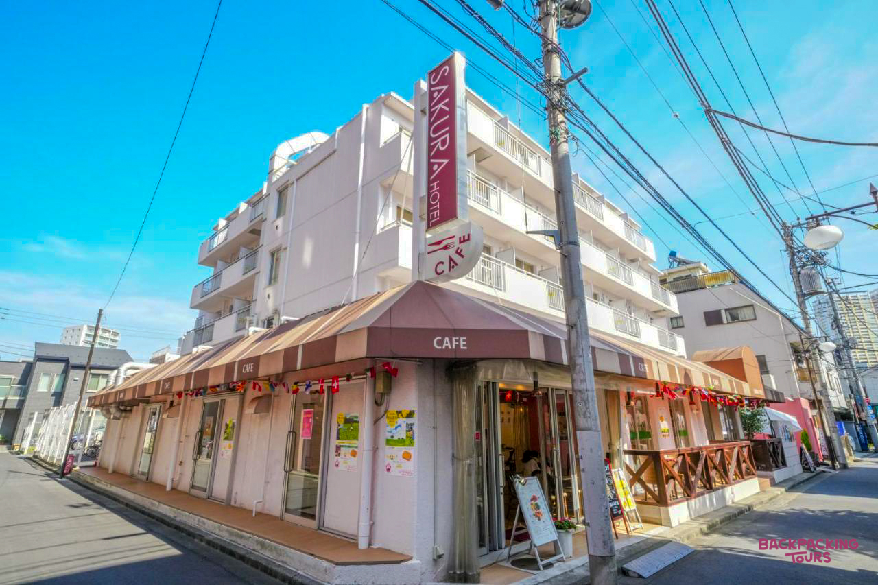 A charming Sakura Hotel and Cafe building on a sunny street corner in Tokyo.