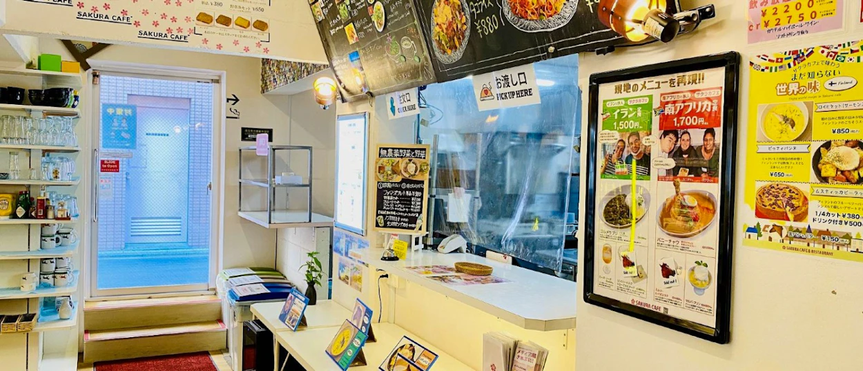 A brightly lit, clean counter area of a small Japanese cafe with menus on the wall.