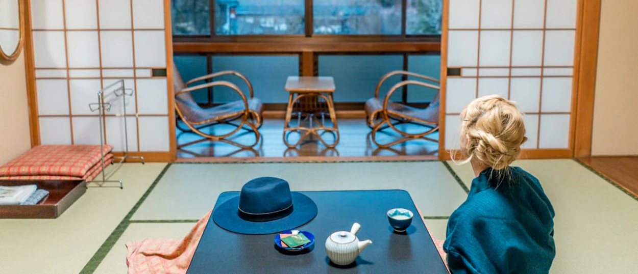 A person sits on tatami mats in a traditional Japanese room, enjoying tea at Koyasan.