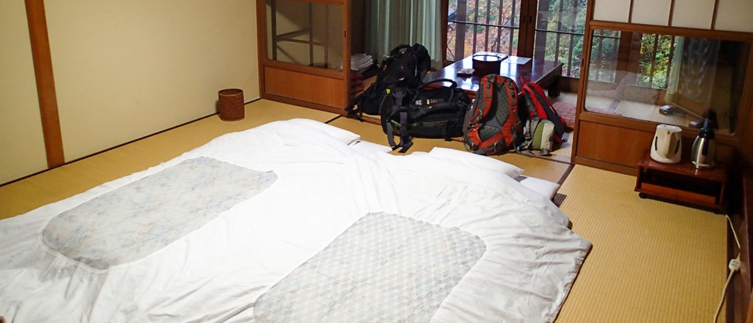 Cozy traditional Japanese room with futons on tatami mats and backpacks, ready for rest in Koyasan.