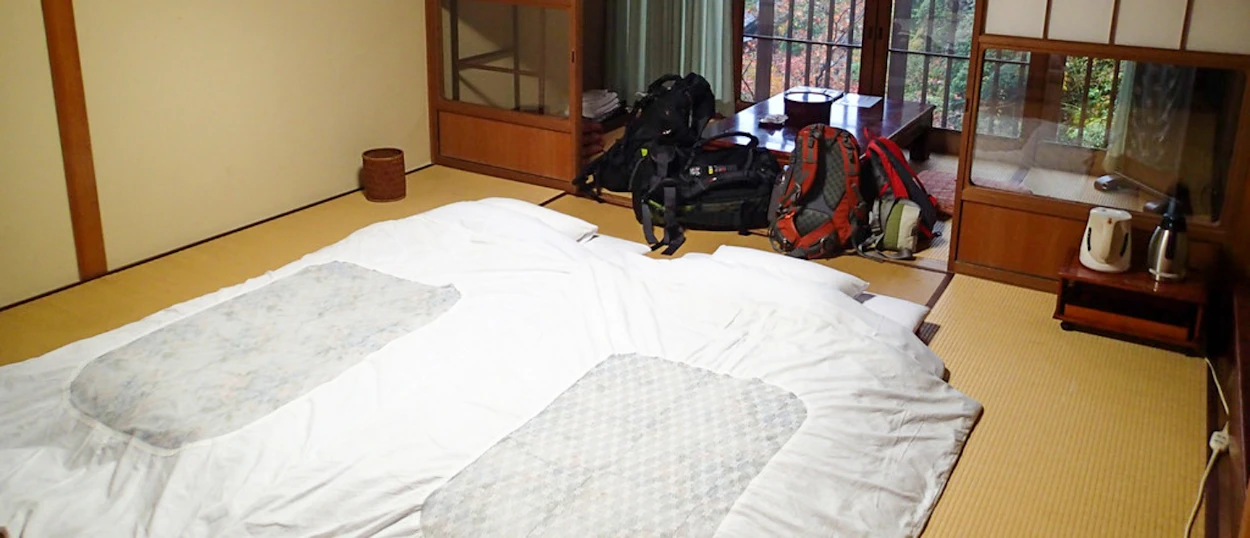 Cozy traditional Japanese room with futons on tatami mats and backpacks, ready for rest in Koyasan.