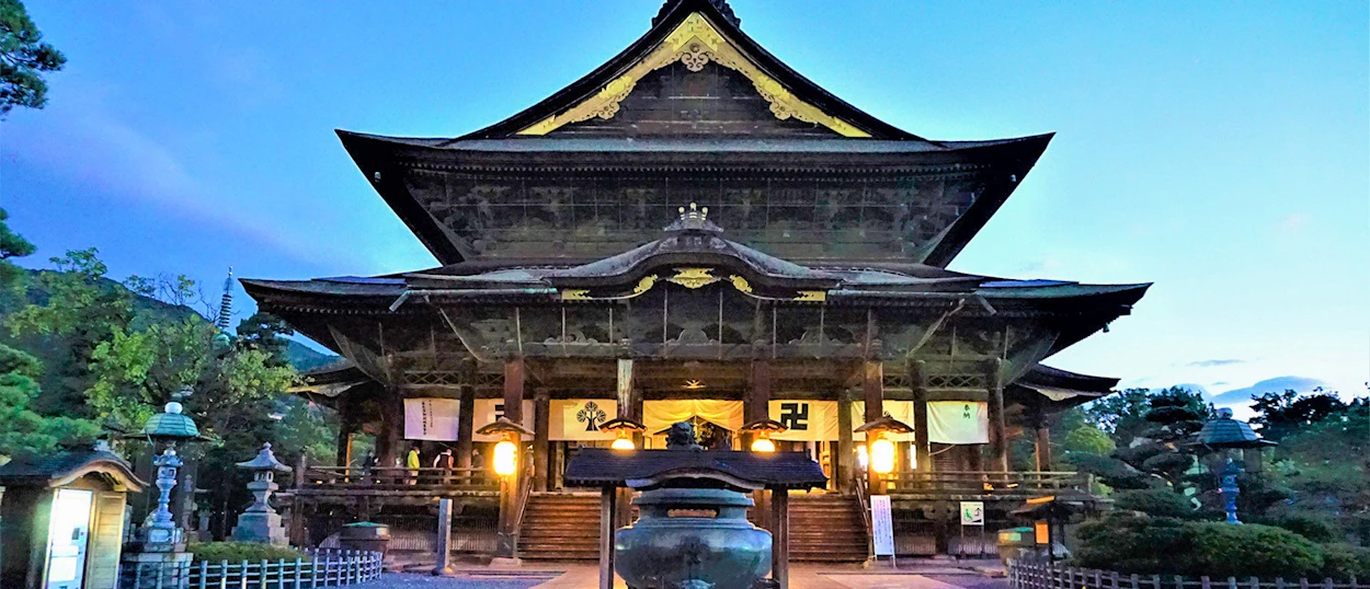 Ornate Japanese temple with lit lanterns at dusk in Takayama, surrounded by serene gardens.
