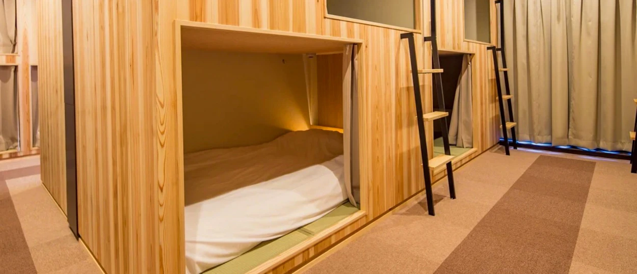 Modern wooden sleeping pods with comfortable bedding in a clean hostel room in Kyoto.