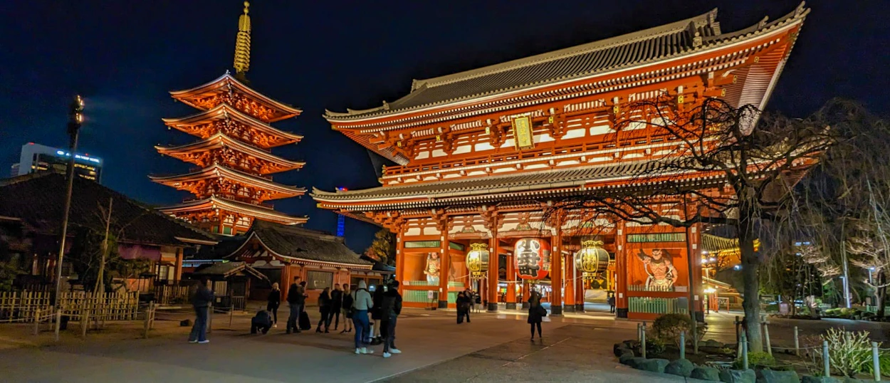 Visitors explore the beautifully illuminated Senso-ji Temple and five-story pagoda in Tokyo at night.