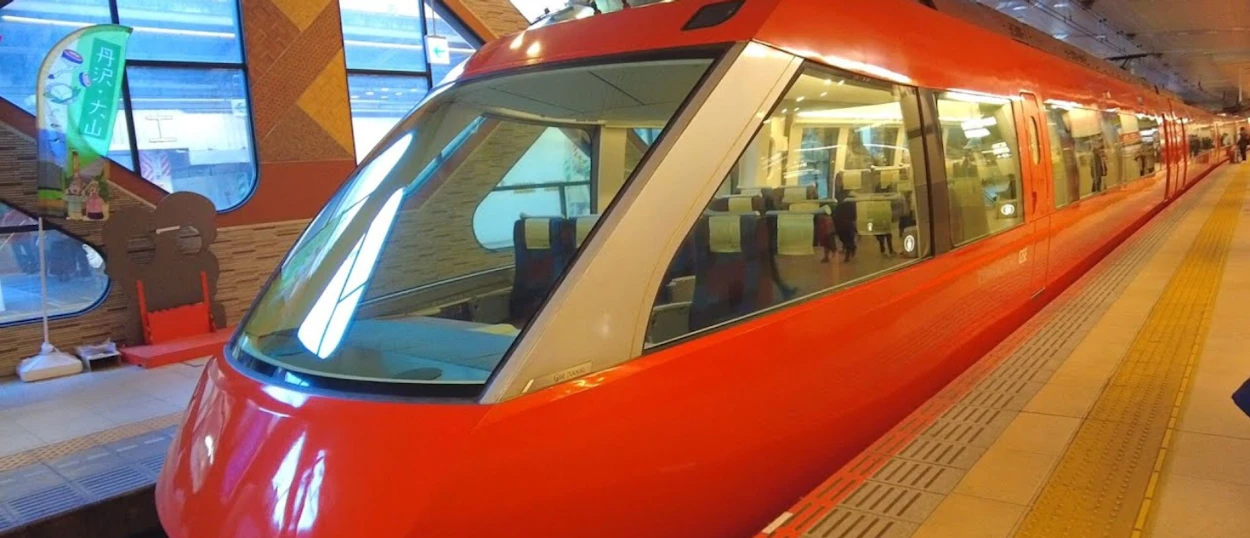 A bright red modern train with panoramic windows at a station platform in Kyoto, Japan.