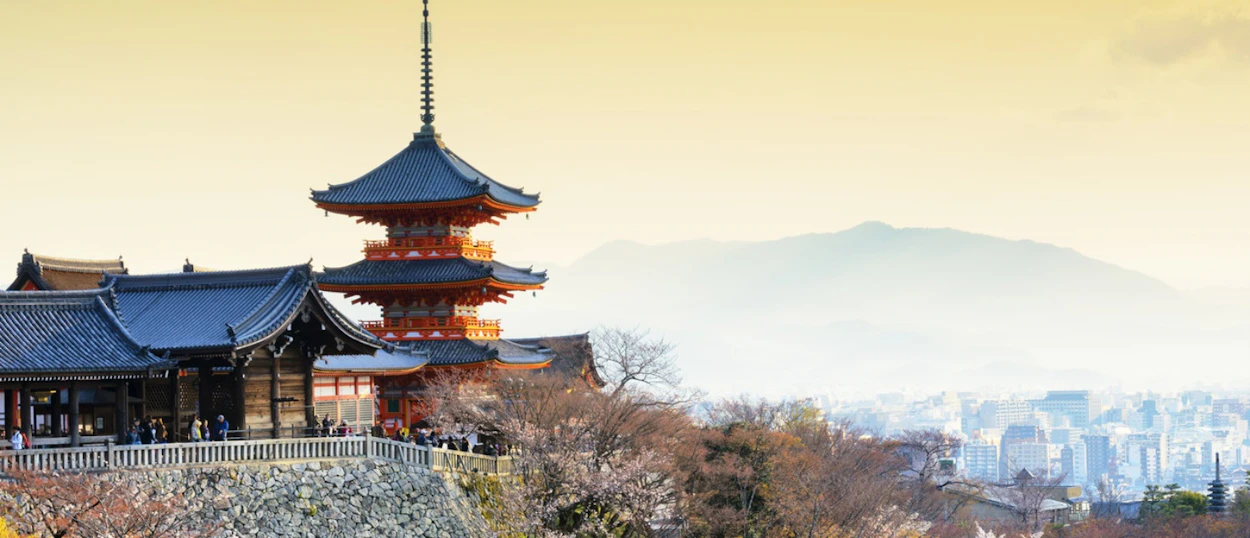 Kiyomizu-dera Temple's pagoda and buildings overlook the city of Kyoto and hazy mountains.