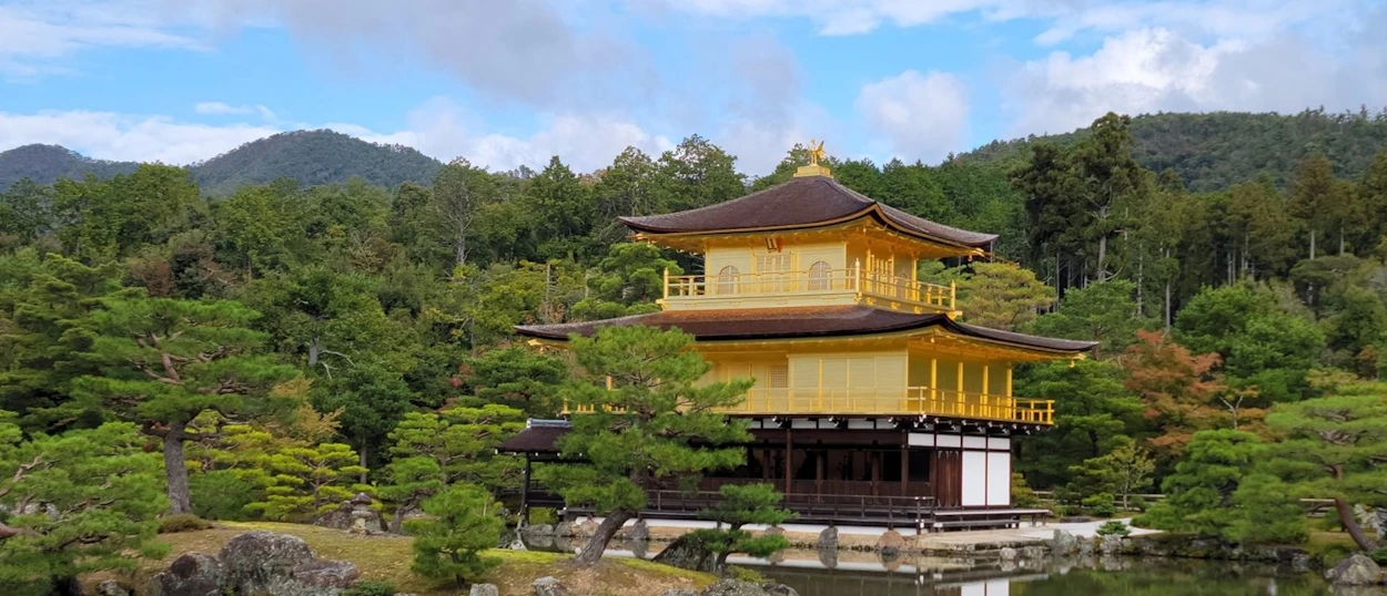 The iconic Golden Pavilion in Kyoto, shimmering gold, reflected in the calm water of its garden.