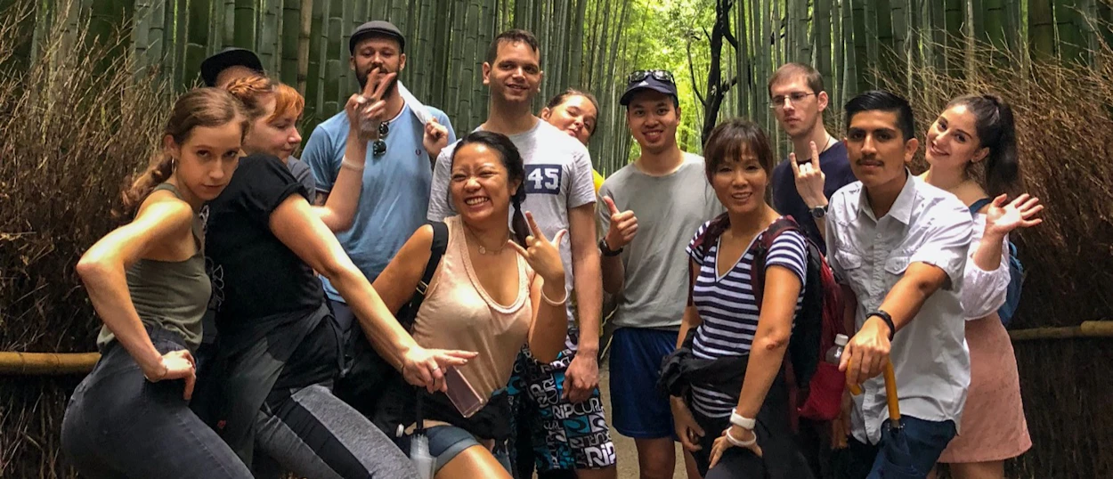 A joyful group of friends posing playfully in the Arashiyama Bamboo Forest in Kyoto.