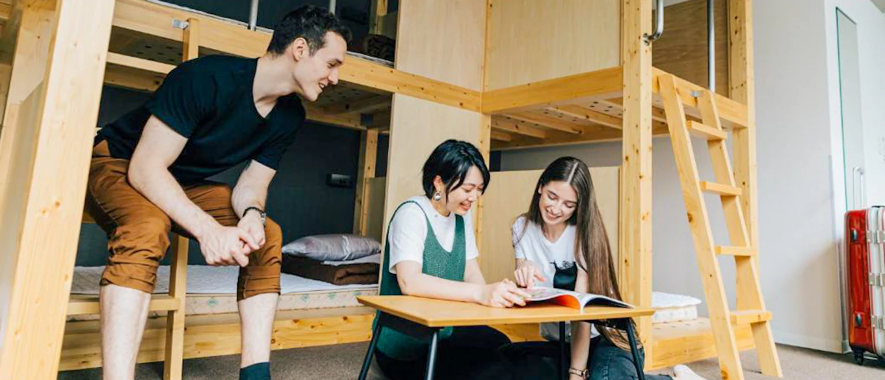 Backpackers relaxing and sharing stories in a comfortable hostel room after a day exploring Osaka.