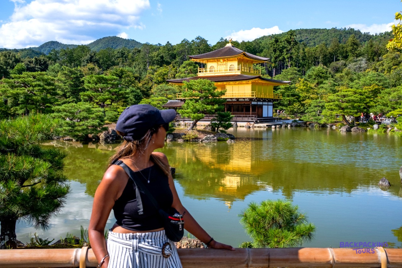 Traveller admiring the Golden Pavilion reflected in its lake in Kyoto
