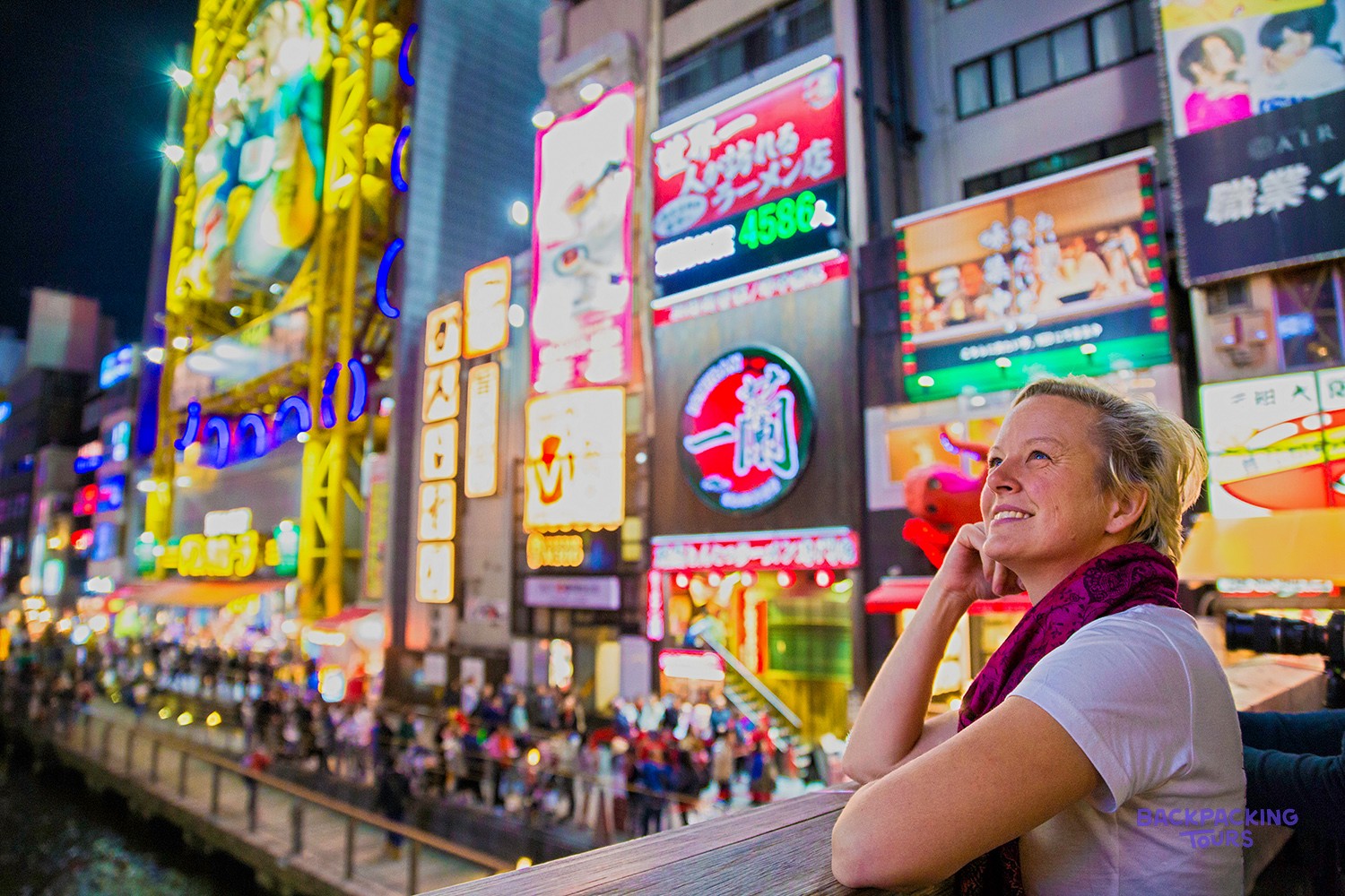 Traveller surrounded by the neon signs of Osaka's Dotonbori