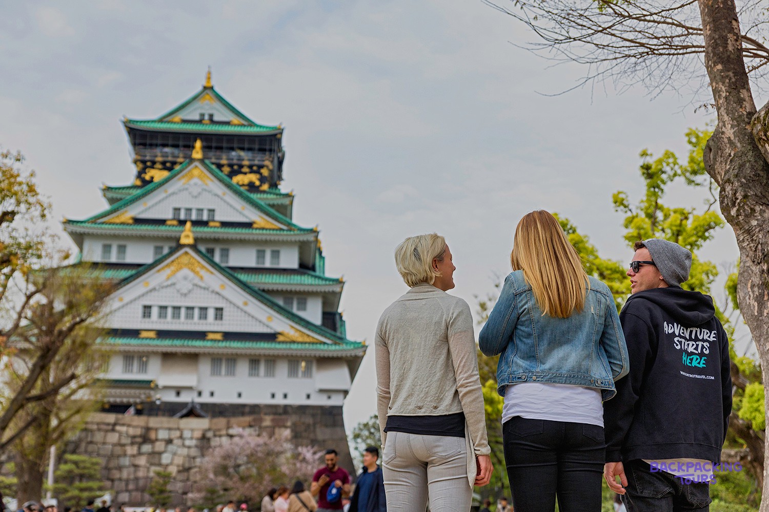 Travellers looking up at Osaka Castle and its surrounding gardens