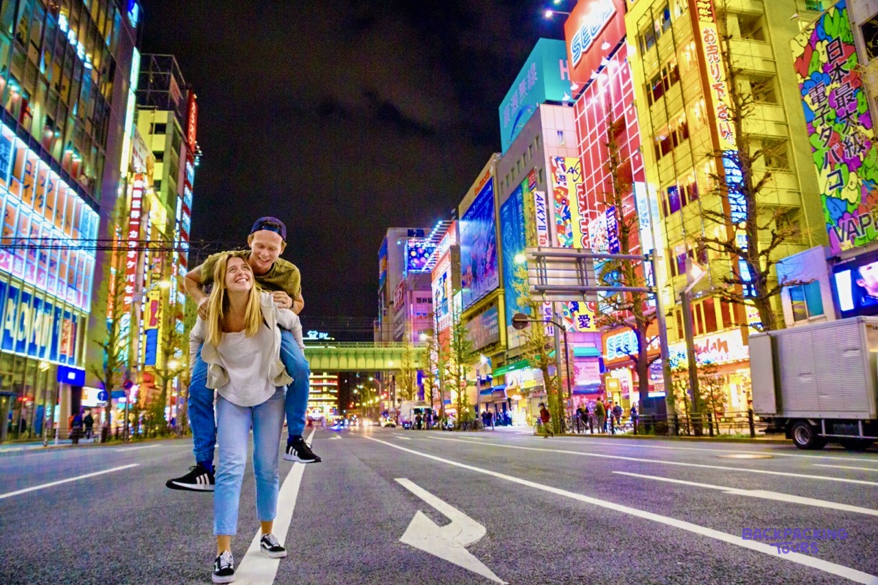 Couple walking Akihabara's neon-lit streets after dark
