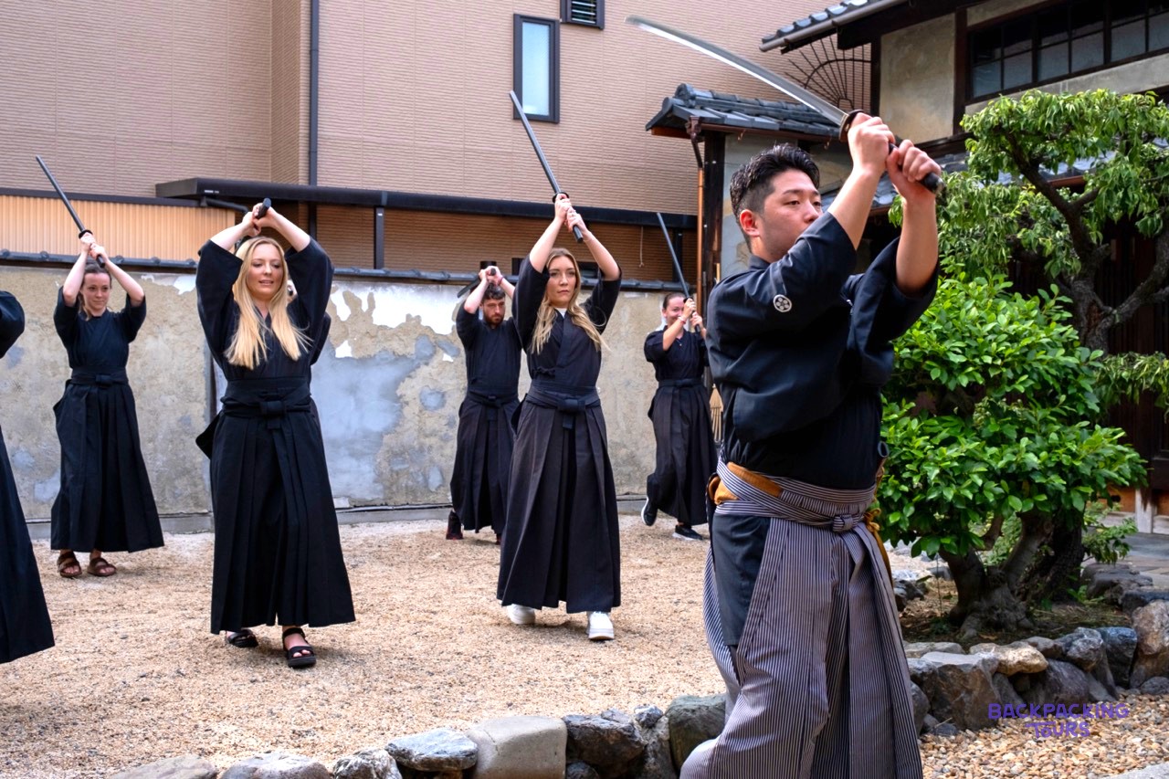 Travellers raising wooden swords during a samurai class in Kyoto