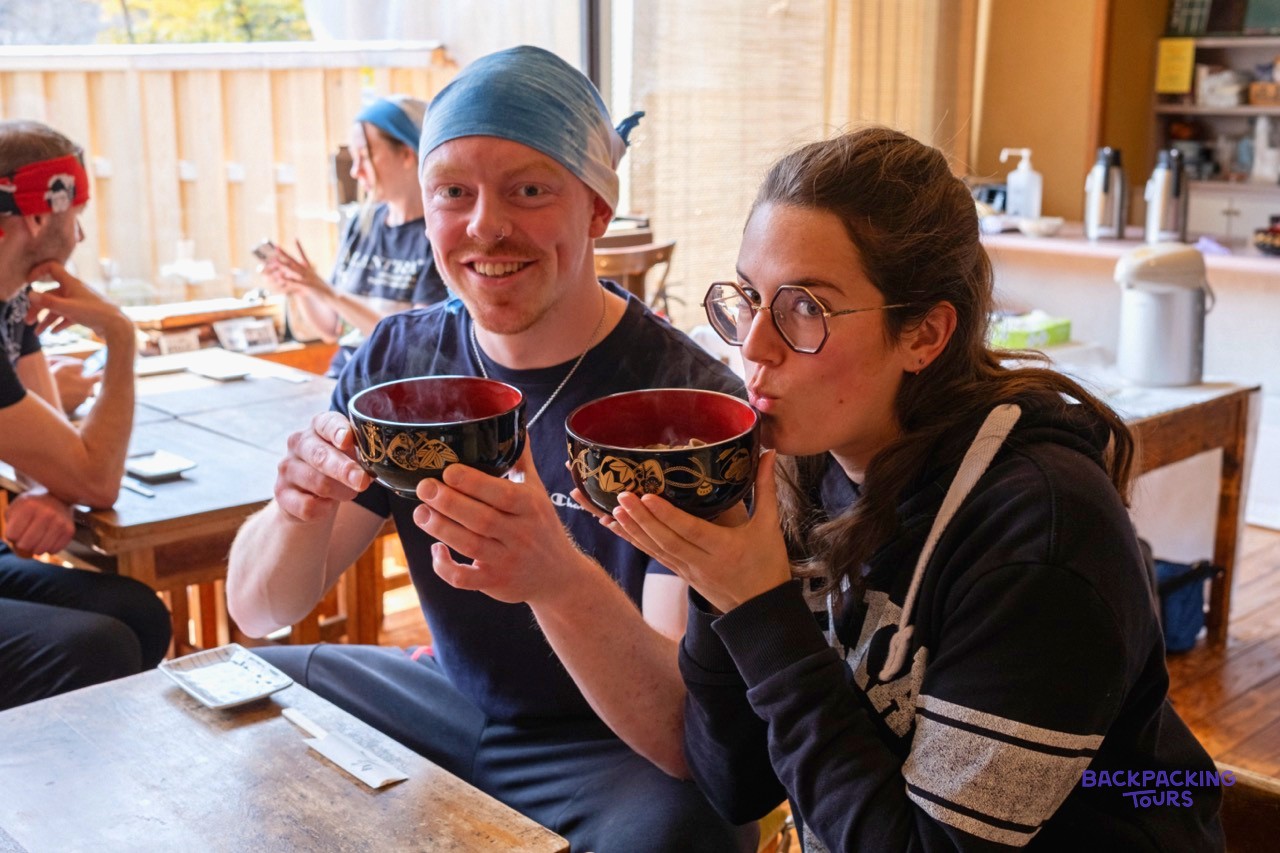 Two travellers tasting the soba noodles they made themselves