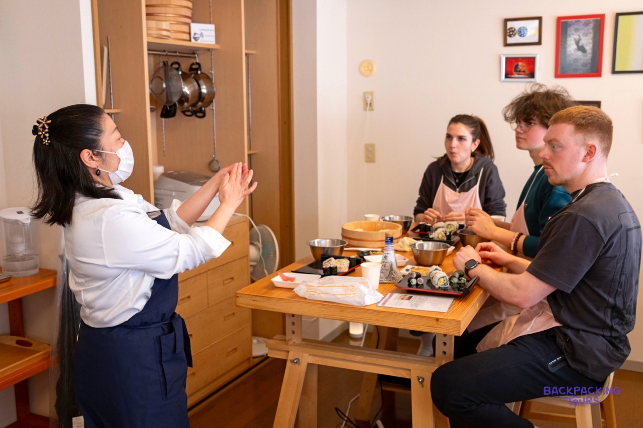 Sushi chef demonstrating hand-rolling to the group in Tokyo