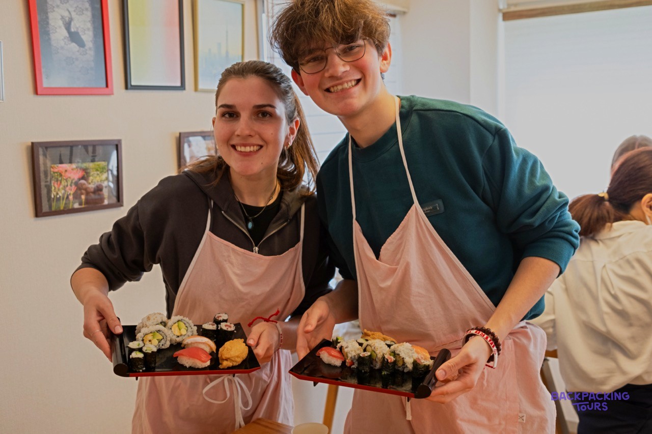 Two travellers in aprons proud of the sushi they rolled
