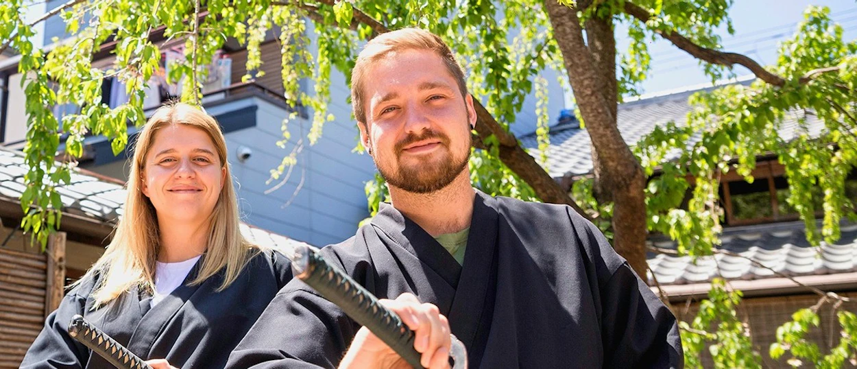 Two travellers dressed in samurai robes holding swords in Kyoto