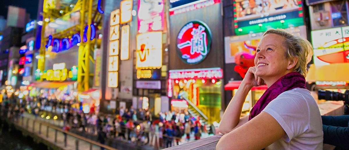Traveller surrounded by the neon signs of Osaka's Dotonbori