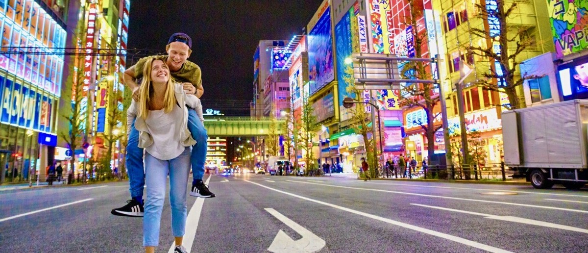 Couple walking Akihabara's neon-lit streets after dark