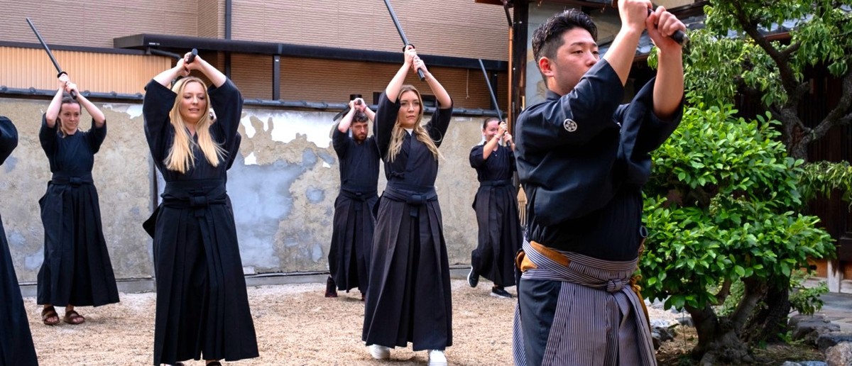 Travellers raising wooden swords during a samurai class in Kyoto