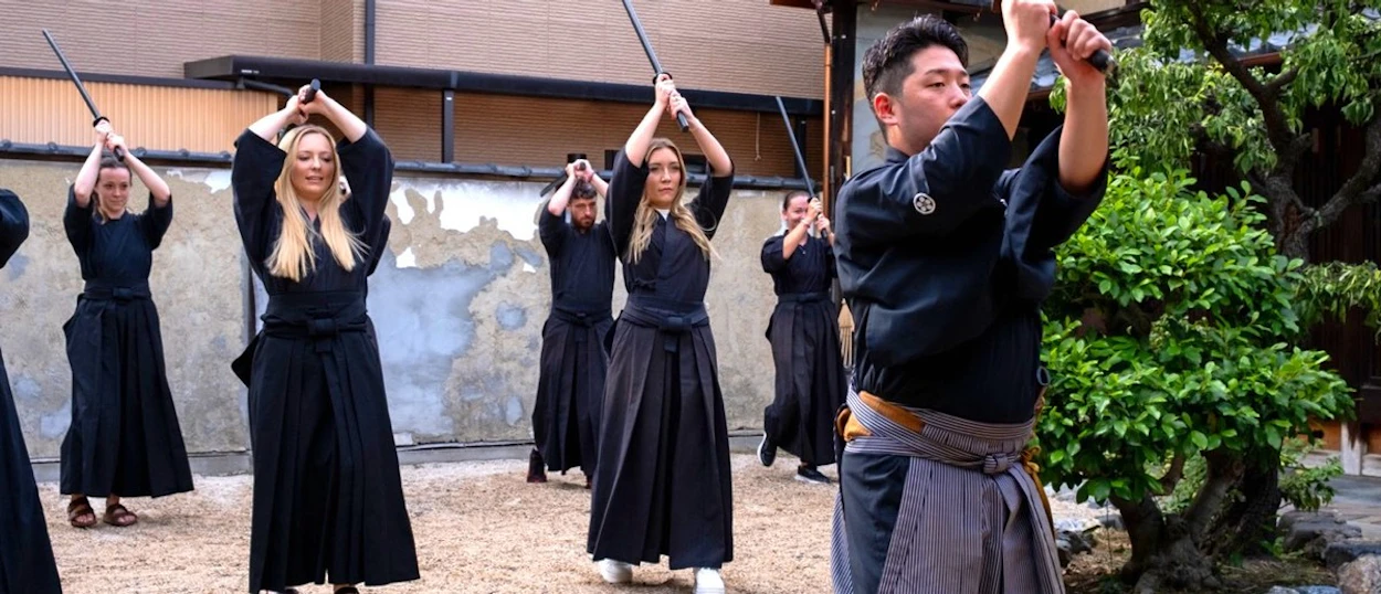 Travellers raising wooden swords during a samurai class in Kyoto