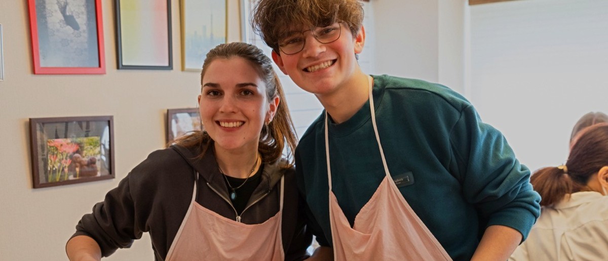 Two travellers in aprons proud of the sushi they rolled