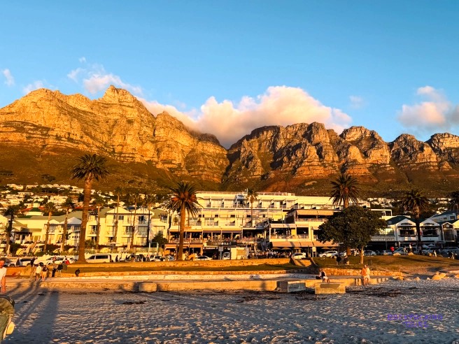 Golden evening light on the Twelve Apostles above palm trees and a beachfront hotel