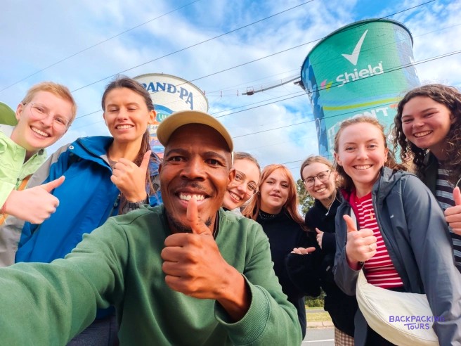 Smiling local guide taking a group selfie with travellers in front of the Orlando Towers