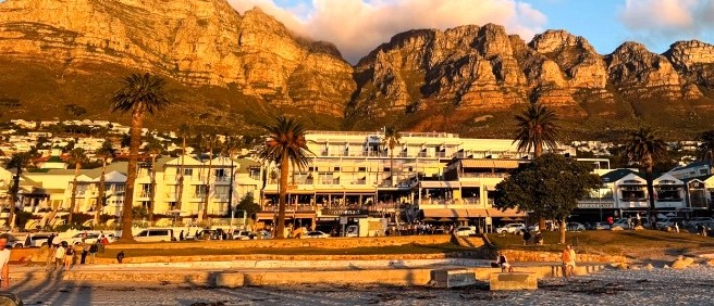 Golden evening light on the Twelve Apostles above palm trees and a beachfront hotel