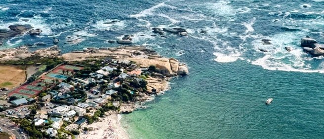 Bird's-eye view of a coastal suburb, a white sand beach and turquoise sea