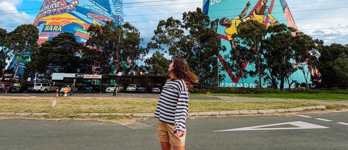 Traveller standing on a quiet road beneath the painted Orlando Towers in Soweto