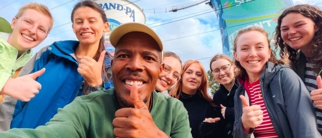 Smiling local guide taking a group selfie with travellers in front of the Orlando Towers