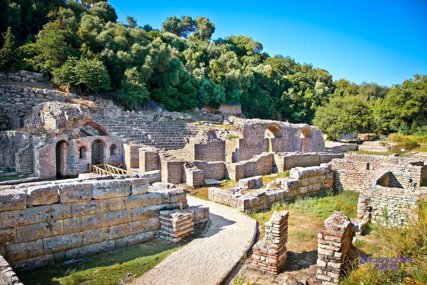 Ancient stone walls and arches among the trees at Butrint Archaeological Park