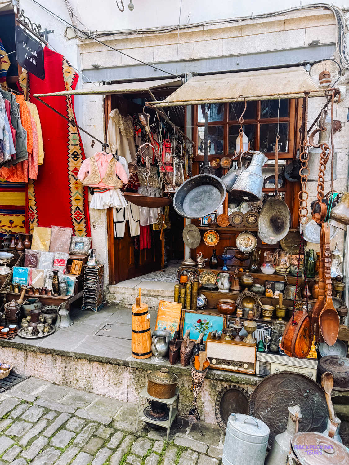 A shop in Gjirokastër's old bazaar hung with copper pots, carpets and traditional costumes