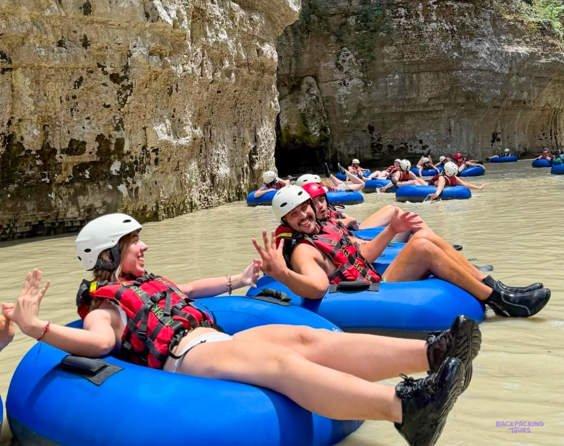 Travellers in helmets and life jackets floating on rubber rings through the Osumi Canyon