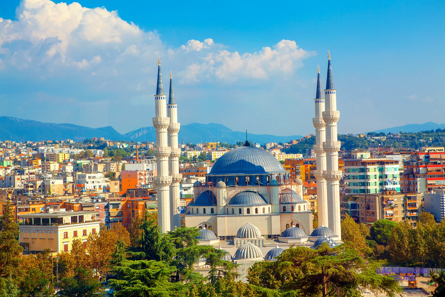 The four white minarets and blue domes of Tirana's Great Mosque above the city