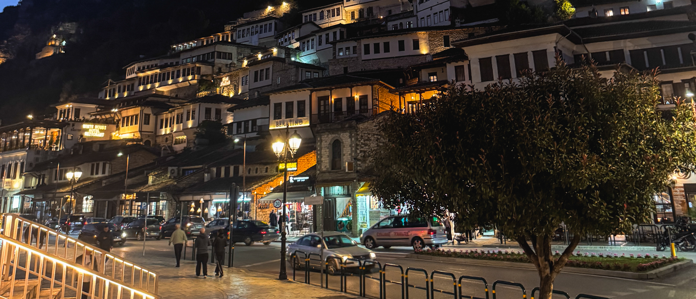 Rows of lit Ottoman houses stacked up the hillside of Berat's Mangalem quarter at night