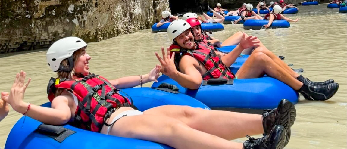 Travellers in helmets and life jackets floating on rubber rings through the Osumi Canyon