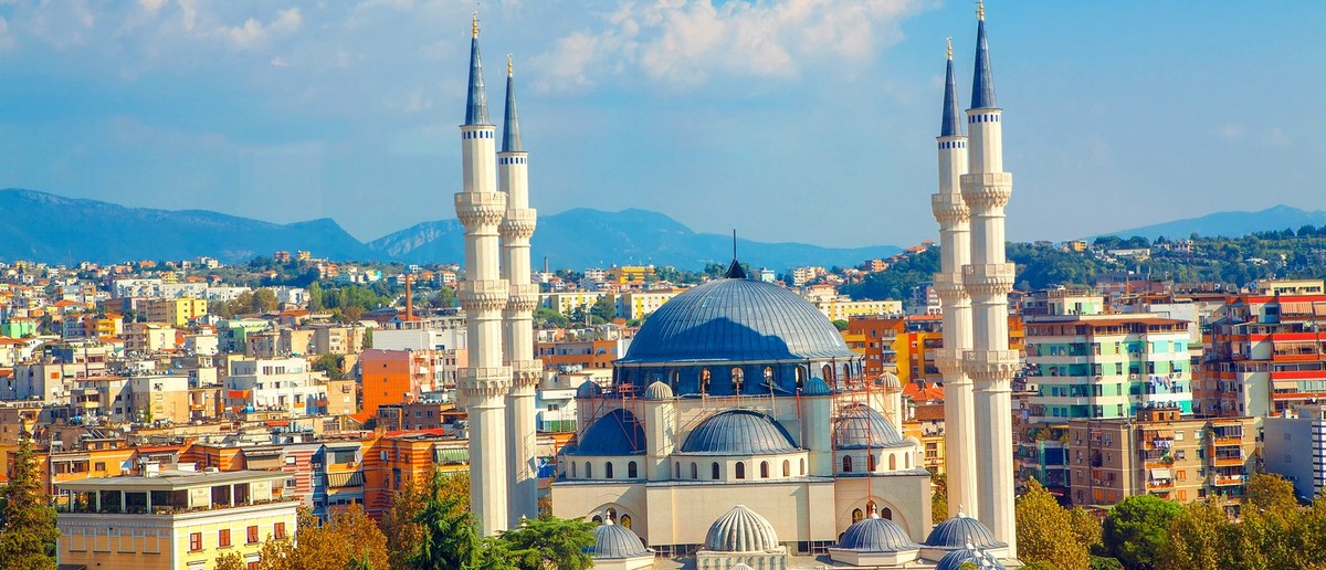 The four white minarets and blue domes of Tirana's Great Mosque above the city