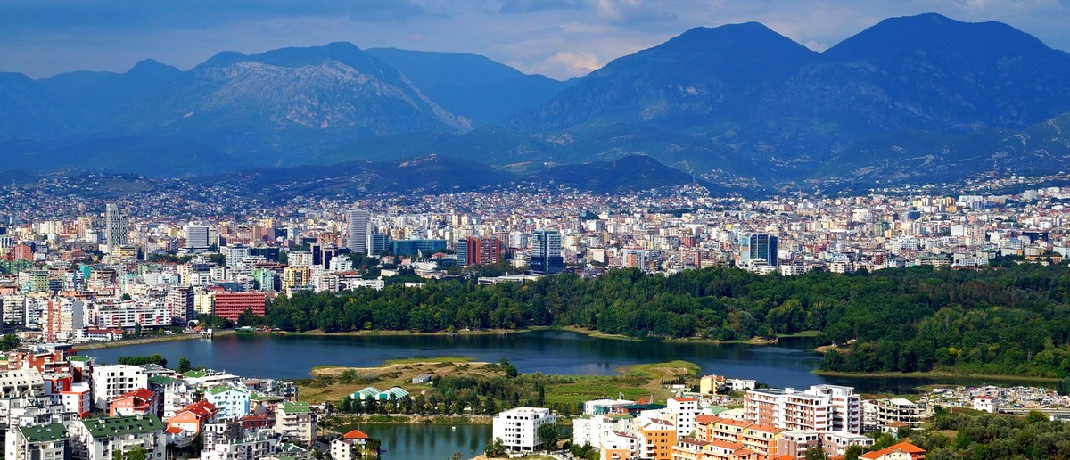 Tirana spread out below the mountains, with the Grand Park lake in the foreground